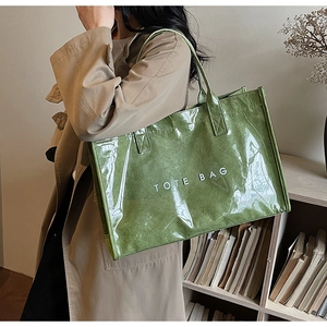 Close-up of a grass green tote bag with gloss texture and white TOTE BAG lettering