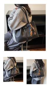Detail of black faux leather tote bag with wooden bead tassel and side buckle strap