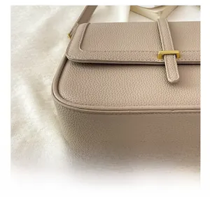 Gros plan sur le cuir grainé et les coutures précises du sac à main carré beige