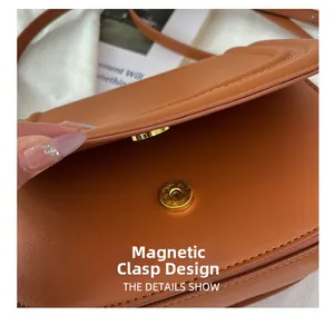 Détail du sac selle marron caramel montrant la boucle magnétique dorée et la texture du cuir