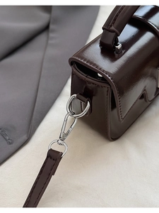 Detailed close-up of glossy chocolate brown PU leather mini bag with silver metal D-rings