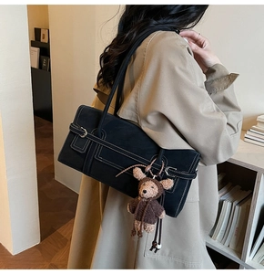 Detail of black faux leather tote with white stitching and cute bear charm accent