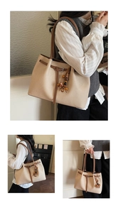 Detail view of large beige tote bag with brown leather straps and beaded tassel charm
