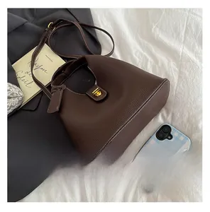 Detail view of dark brown bucket bag with lychee grain leather and golden metal clasp