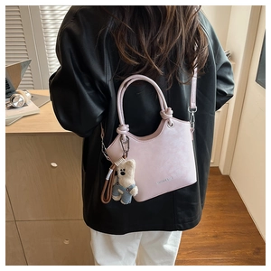 Detail of pink leather bucket bag with knot handle and cute bear plush charm