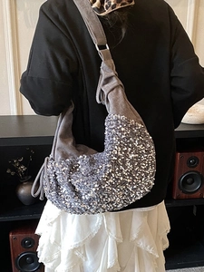 Sparkly silver sequin hobo bag with drawstring side detail worn by model indoors