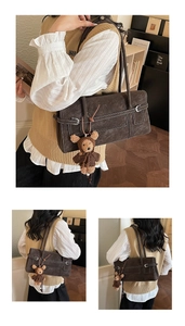 Detail of dark brown retro underarm bag with contrast stitching and cute bear charm