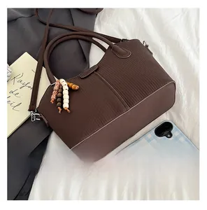 Détail du sac à main marron avec texture plissée et accessoire perlé de style ethnique