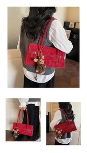 Red leather tote bag featuring white contrast stitching and a brown plush bear charm