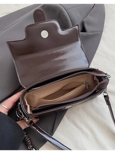 Interior detail of a dark brown glossy leather handbag showing inner compartments