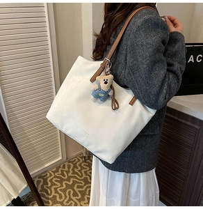 Detailed shot of white PU leather tote bag with brown straps and cute bear pendant charm
