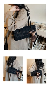 Close-up of black matte tote with white contrast stitching and bear charm