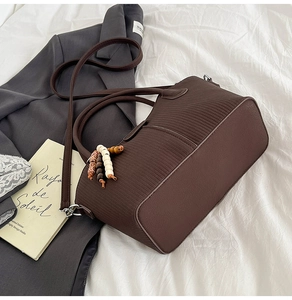 Gros plan d'un sac seau en cuir marron foncé avec un élégant pendentif en perles
