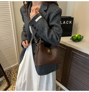 Close-up of dark brown lychee leather bucket bag with elegant gold twist-lock buckle
