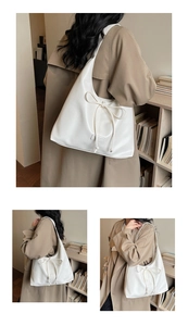 Detail of white leather hobo bag with drawstring bow and brand tag on a model