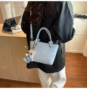 Detail of light blue PU leather handbag with adjustable strap and cute teddy bear charm
