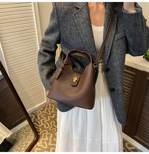 Detail of dark brown lychee grain leather bucket bag with gold clasp on model