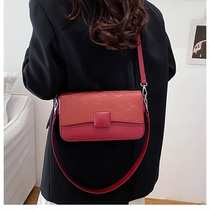 Detail of red striped leather flap bag on black blazer with silver metal hook hardware