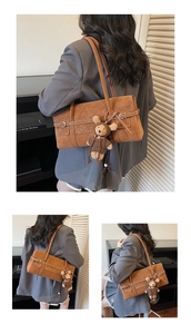 Detail of a brown vintage shoulder bag featuring a silver buckle and cute bear plush charm