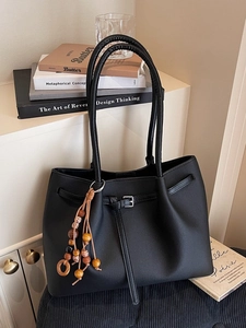 Minimalist black matte leather tote bag with wooden bead charm and silver buckle detail