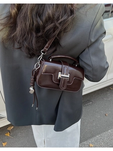Deep coffee small crossbody bag with silver hardware and spherical charm on a model