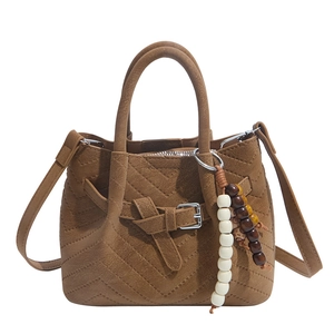 Brown leather basket handbag with herringbone stitching and beaded charm accessory