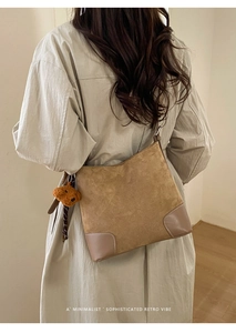 Détail du sac seau en daim marron avec surpiqûres blanches et charme d'ours en peluche