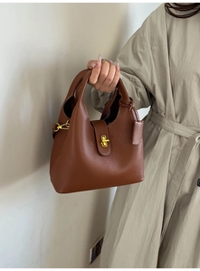 Detail of brown lychee grain leather bucket bag with gold lock and textured finish