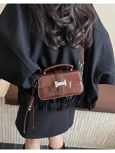 Detailed back view of a brown vintage crossbody bag worn by a model in soft lighting