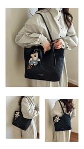 Detail showing the black leather tote bag texture and a cute plush bear charm accessory