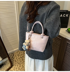 Detail of light pink tote bag with XIAOCHE BAGS text and a cute bear charm accessory