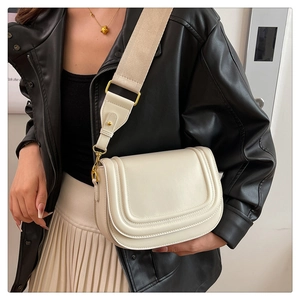Gros plan du sac de selle montrant le cuir blanc et la bandoulière en toile large
