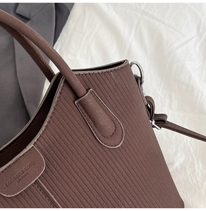 Vue détaillée de la poignée du sac en cuir marron foncé et de la texture gaufrée verticale