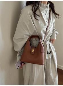 Close-up of brown litchi pattern leather bucket bag with elegant gold twist lock buckle