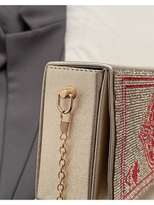 Vue macro d'une pochette dorée montrant les strass et les détails de broderie rouge