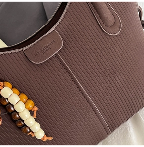Détail de texture cuir marron à rayures avec perles en bois décoratives du sac