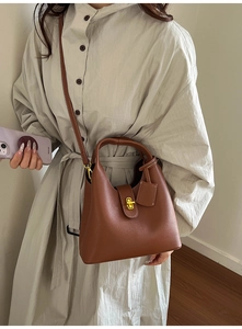 Macro detail of brown litchi pattern leather bucket bag with gold turn-lock buckle