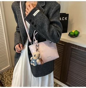 Pink PU leather bucket bag with cute teddy bear charm shown worn as a crossbody purse