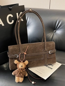 Retro brown suede tote bag with contrast stitching and bear charm on a dark sofa