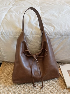 Sac fourre-tout vintage marron en similicuir avec cordon à nœud sur tapis beige tissé