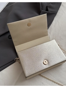 Détail d'une pochette de soirée dorée avec texture métallique et fermoir magnétique