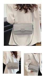 Detail view of the gray-blue rectangular flap bag with textured leather and metal hooks