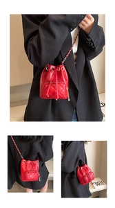 Détail du sac seau en cuir matelassé rouge avec chaîne dorée et fermeture à cordon