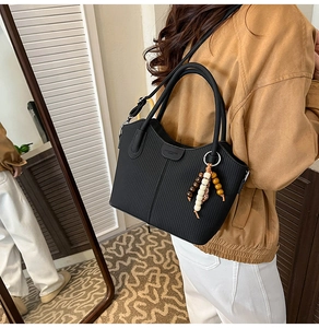 Détail du sac seau noir à rayures verticales avec perles en bois et poignée ronde