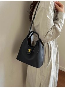 Detail of black pebble leather bucket bag with gold metal lock and white contrast stitching