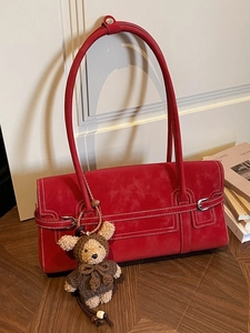 Red retro suede tote bag with white stitching and bear charm on wooden table