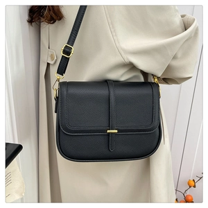 Détail du sac bandoulière en cuir grainé noir avec finitions dorées et sangle décorative