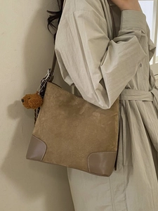 Sac bandoulière en daim marron avec breloque ours et design trapèze porté par un modèle