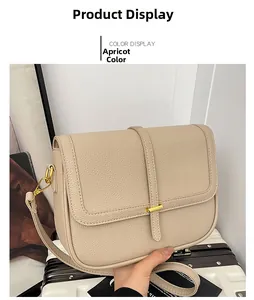 Détail du sac bandoulière beige en cuir texturé litchi avec boucle dorée et lanière