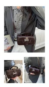 Detail of a dark brown vintage crossbody bag with a silver buckle and top handle